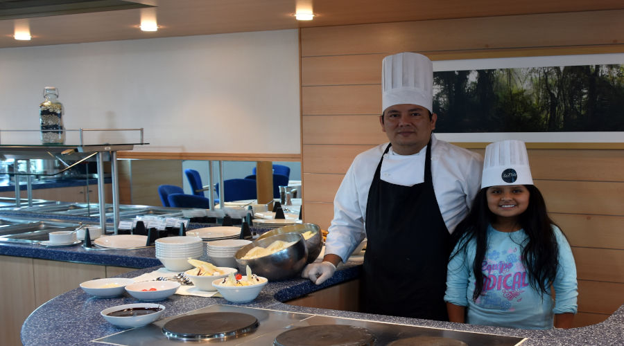Child visitor stands next to a cruise´s head chef