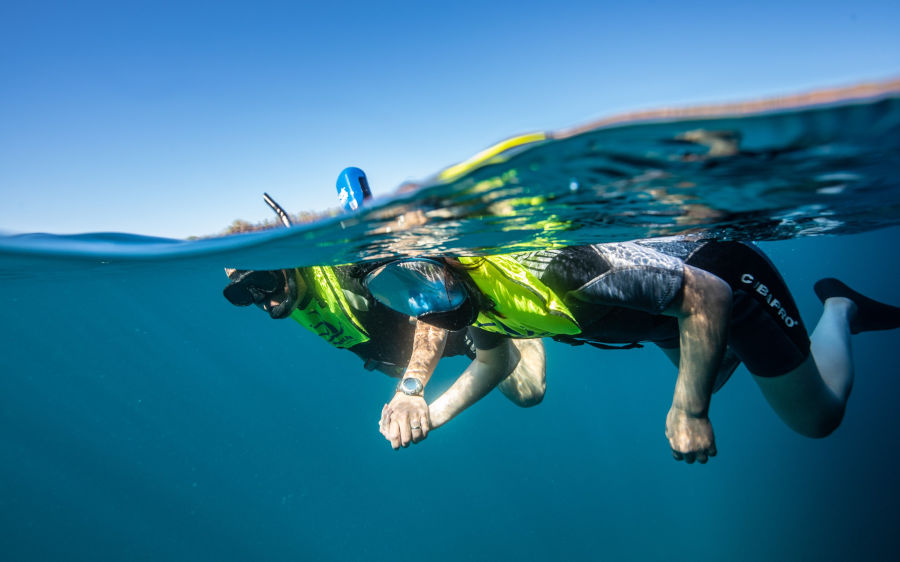 Pareja tomada de la mano mientras practica buceo de superficie en Galápagos.
