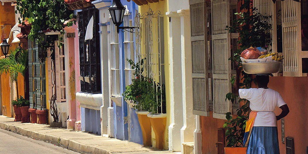 Colorful colonial street in Cartagena’s historic center with vibrant facades, potted plants, and traditional balconies.
