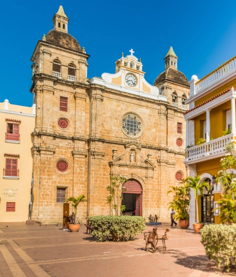 Santo Domingo Church in Cartagena’s historic center with its stone façade, clock, and surrounding colonial buildings.