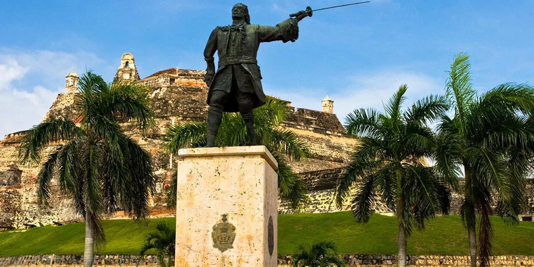 Statue of Blas de Lezo pointing toward the sea, set against the historic walls of Cartagena in Colombia.